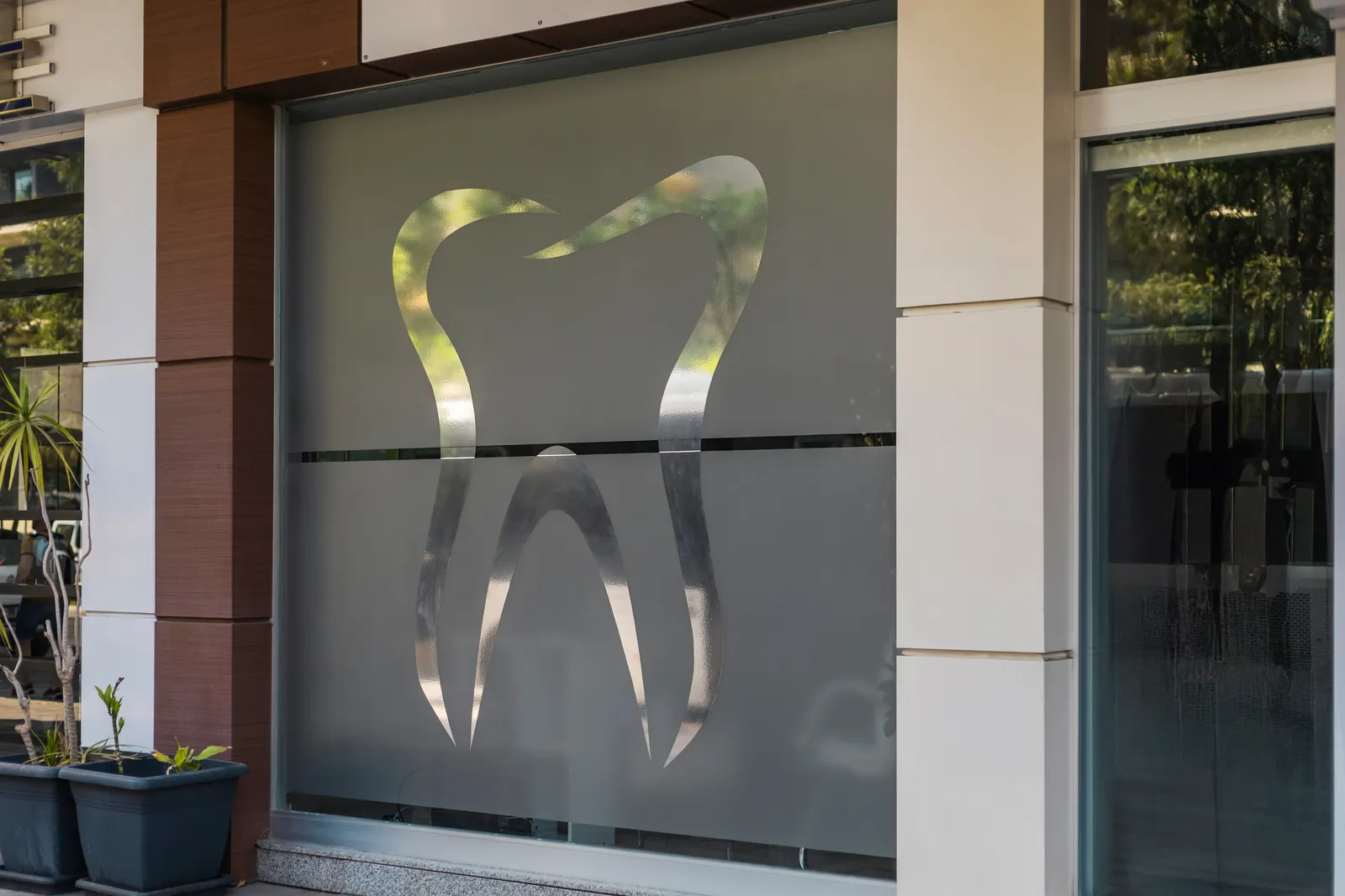 Dental practice storefront with a large tooth symbol etched on frosted glass in daylight